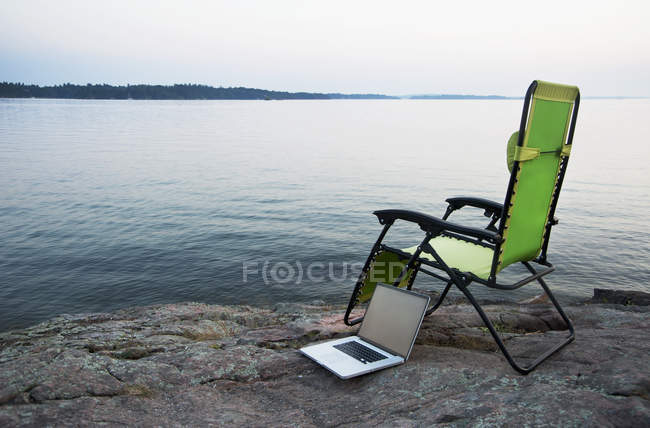 Ноутбук на стільці на галявині біля віддалених річок, Канада — стокове фото