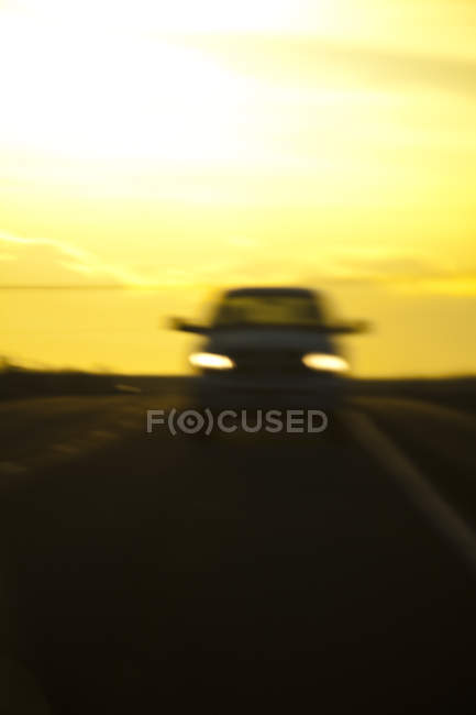 Vista turva do carro na estrada à noite com céu amarelo — Fotografia de Stock