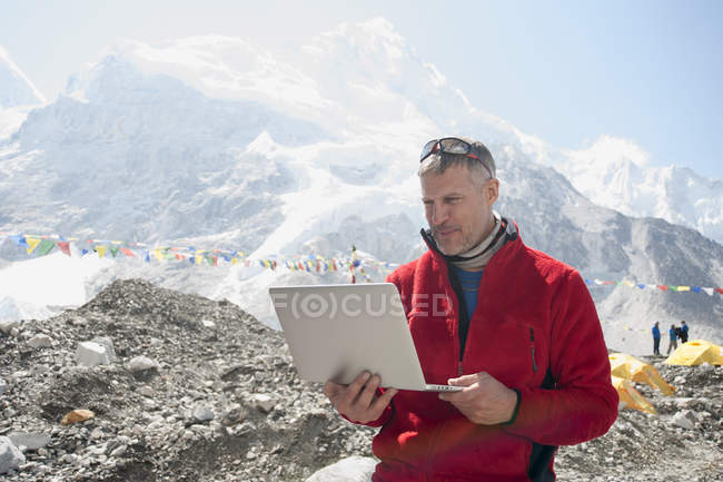 Hombre usando laptop en montañas nevadas, campamento base del Everest, Nepal, Asia - foto de stock