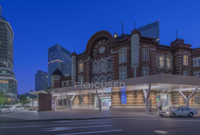 Edificios urbanos y estación de ferrocarril iluminados por la noche, Marunouchi, Tokio, Japón - foto de stock