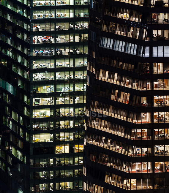 Edificios iluminados de gran altura con oficinas por la noche - foto de stock