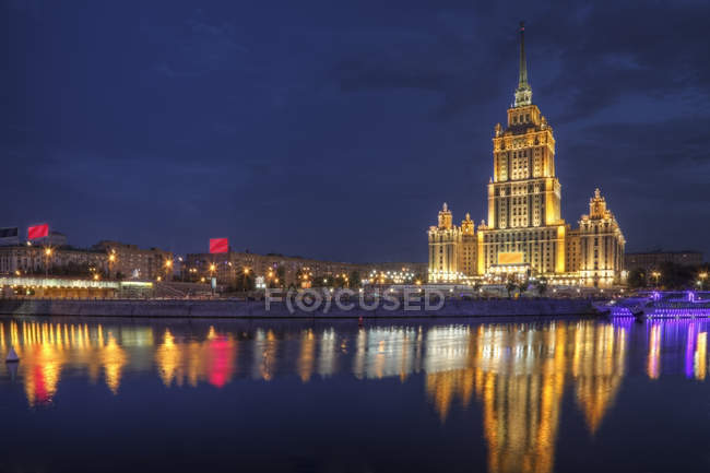 Ciudad horizonte iluminado con reflejo en el agua por la noche, Moscú, Rusia - foto de stock