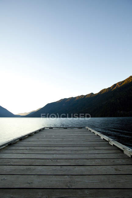 Деревянная палуба у озера под голубым небом — стоковое фото