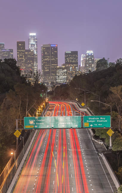 Los angeles city skyline über der vielbefahrenen Autobahn nachts beleuchtet, kalifornien, vereinigte staaten — Stockfoto