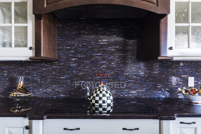 Checkered teapot on stove in kitchen — Stock Photo