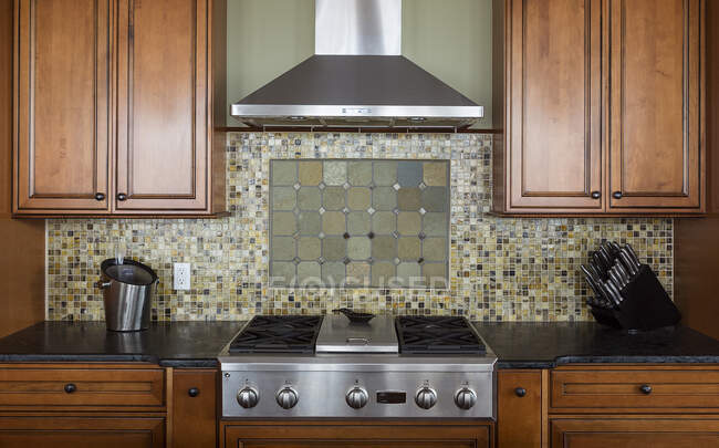 Tile back splash, ventilation hood and stove in kitchen — Stock Photo