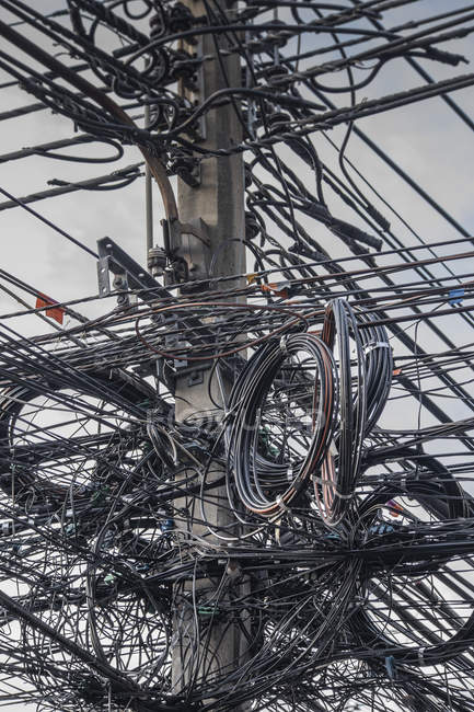 Vue à faible angle des lignes électriques enroulées sur un pôle industriel — Photo de stock