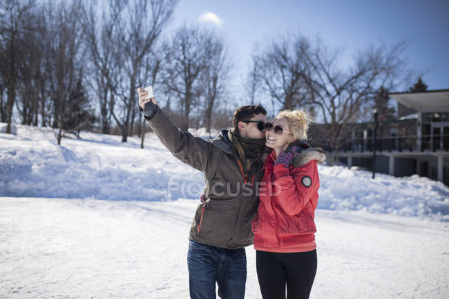 Кавказька пара беручи селфі в зимовому парку — стокове фото