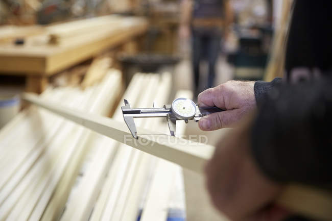 Carpintero midiendo tablón de madera en taller - foto de stock