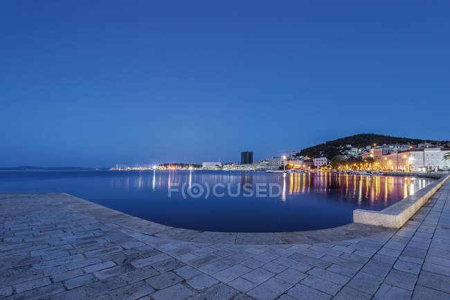 Bord de l'eau trottoir, bateaux éclairés et quai au crépuscule, Split, Croatie — Photo de stock