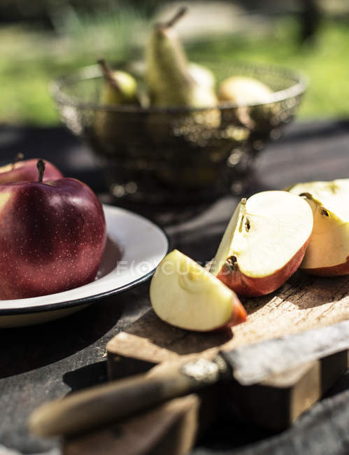 Manzanas en rodajas en la mesa al aire libre a la luz del sol . - foto de stock