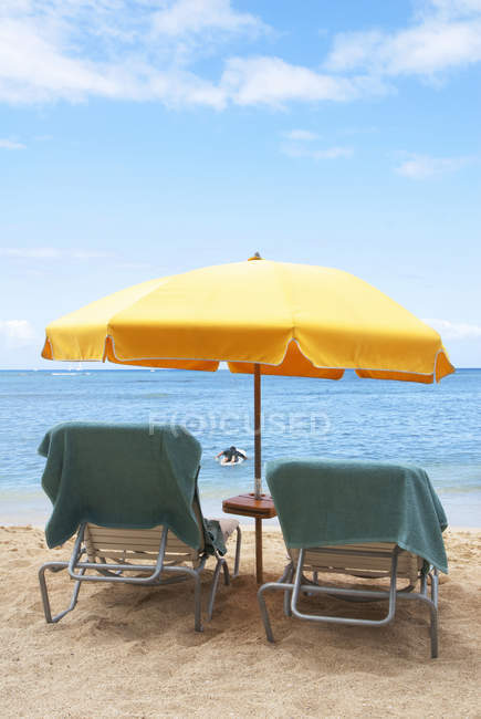 Lawn chairs and umbrella on beach, Hawaii, USA — Stock Photo