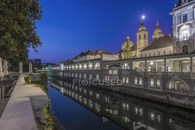 Church and houses reflection in water of canal, Ljubljana, Central Slovenia, Slovenia — Stock Photo
