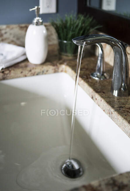 Eau provenant du robinet dans l'évier de la salle de bain moderne — Photo de stock