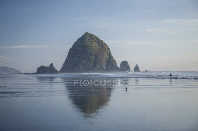 Haystack Rock reflejándose en el océano, Cannon Beach, Oregon, Estados Unidos - foto de stock