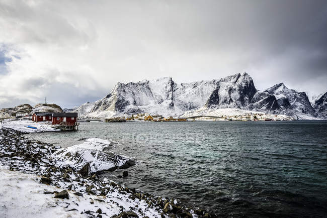 Montagnes enneigées surplombant le littoral rocheux, Reine, Îles Lofoten, Norvège — Photo de stock