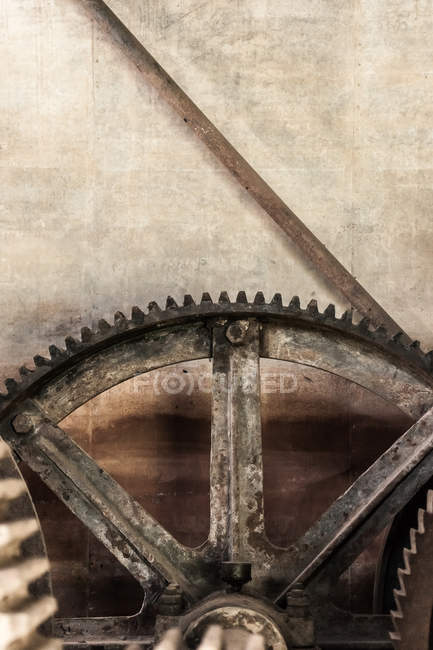 Крупный план ржавчины металлических шестерен против ворчливой стены — стоковое фото