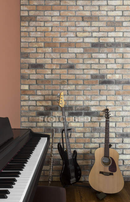 Guitares et piano près d'un mur de briques — Photo de stock