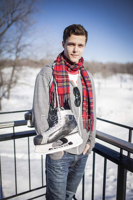 Young Caucasian man carrying ice skates in winter — Stock Photo
