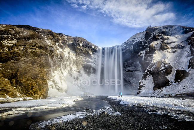 Vue de dos du photographe prenant une photo de la cascade de skogafoss, iceland — Photo de stock