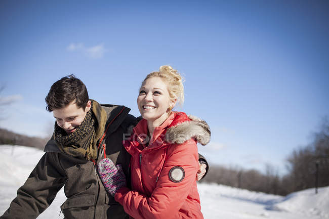 Joven pareja alegre abrazándose en el parque de invierno a la luz del sol - foto de stock