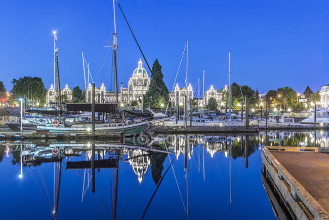 Parliament Buildings and harbor boats illuminated at dawn, Victoria, British Columbia, Canada — Stock Photo