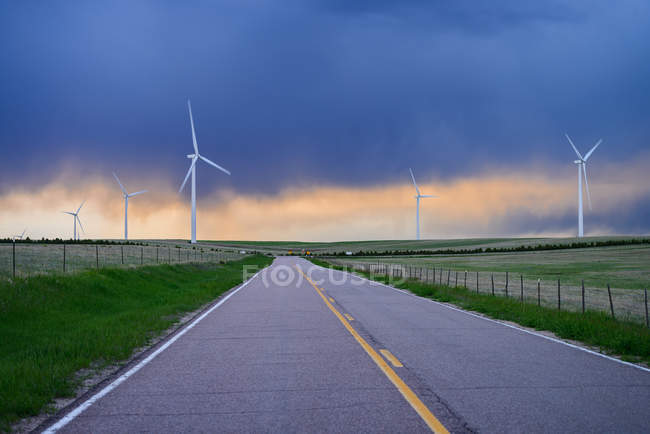 Wind turbines near road at sunset, Colorado, USA — Stock Photo
