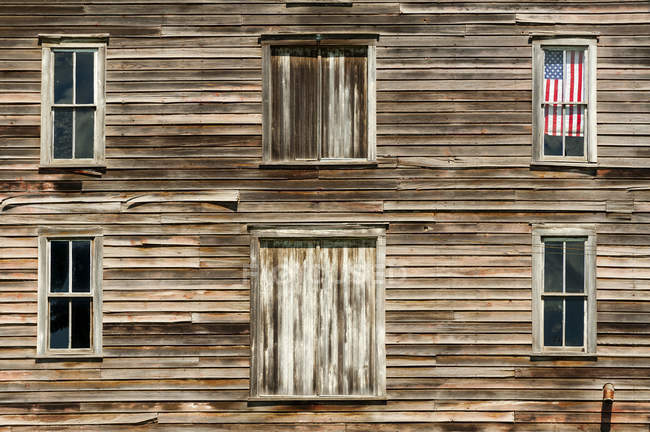 Casa de madeira exterior com bandeira americana na janela — Fotografia de Stock