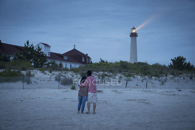 Rear view of couple watching lighthouse at beach of New Jersey, USA — Stock Photo