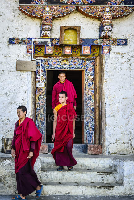 Asian monks walking out temple doorway — Stock Photo