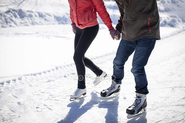 Baixa seção de patinação no gelo casal no lago gelado nevado no inverno — Fotografia de Stock