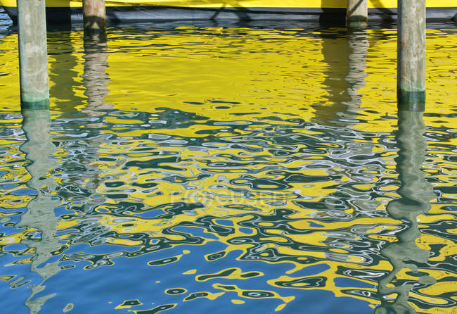 Gelbes Boot reflektiert im Wasser mit Holzstangen. — Stockfoto