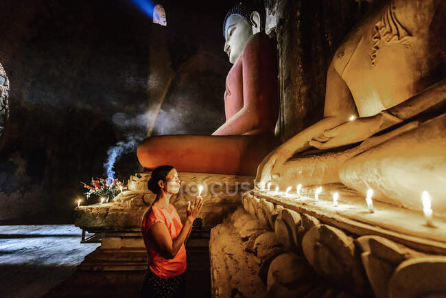 Mujer asiática encendiendo vela en templo - foto de stock