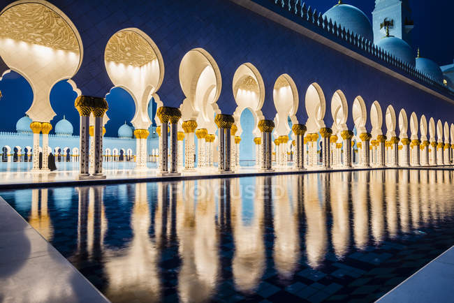 Kunstvoll gekachelte Bögen der großen Moschee, die nachts erleuchtet, abu dhabi, vereinigte arabische Emirate — Stockfoto
