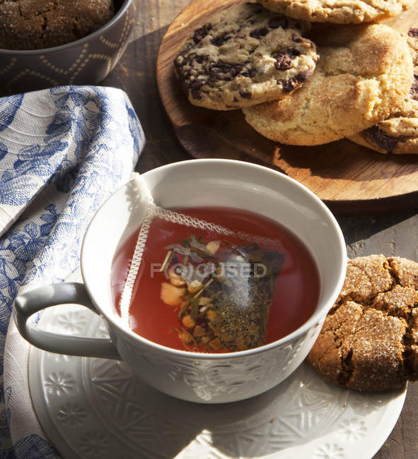 Крупним планом чашка чаю з печивом на дерев'яній тарілці — стокове фото