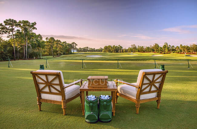 Cadeiras e bolas de golfe na faixa de condução — Fotografia de Stock