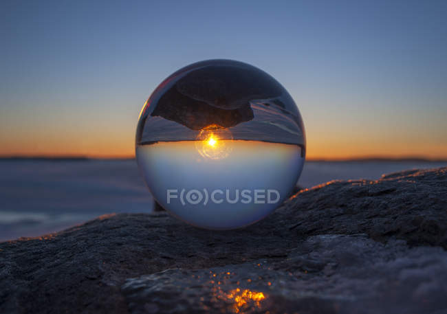 Primer plano del horizonte del atardecer invertido en esfera de vidrio en la playa - foto de stock