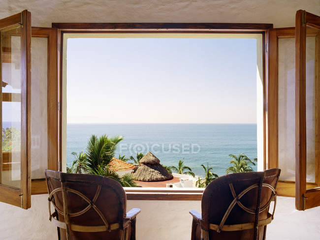 Cadeiras vazias de frente para a janela aberta com vista para o oceano Pacífico — Fotografia de Stock