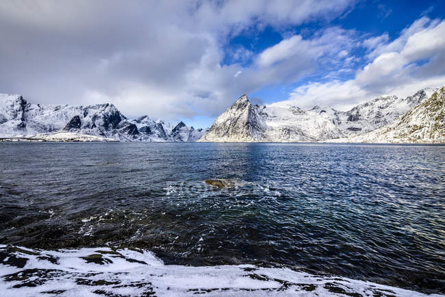 Montañas nevadas con vistas al océano, Reine, Islas Lofoten, Noruega - foto de stock