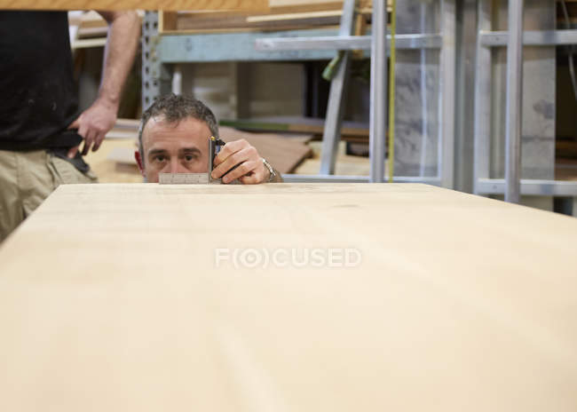Tischler misst Holz im Werkstattinnenraum. — Stockfoto