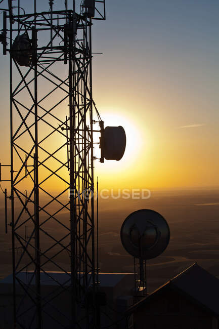Silhouette de la torre de comunicaciones contra el cielo del sol - foto de stock