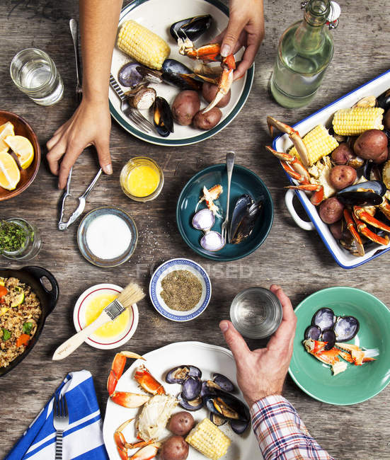 Vista di angolo alto di mani di coppia a cena di frutti di mare — Foto stock