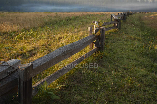 Wooden fence in rural landscape at sunset — Stock Photo
