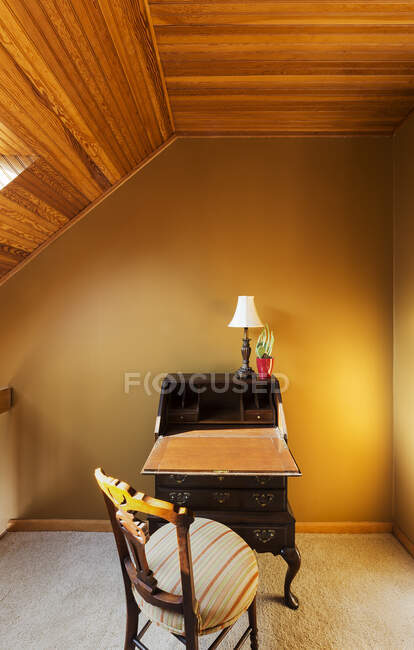 Antique desk under sloped wooden ceiling — Stock Photo