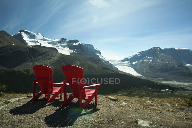 Red lawn chairs near scenic mountain landscape — Stock Photo