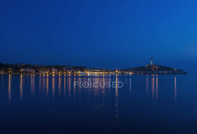 Riflessione sulla città costiera illuminata in acque tranquille, Rovigno, Istria, Croazia — Foto stock