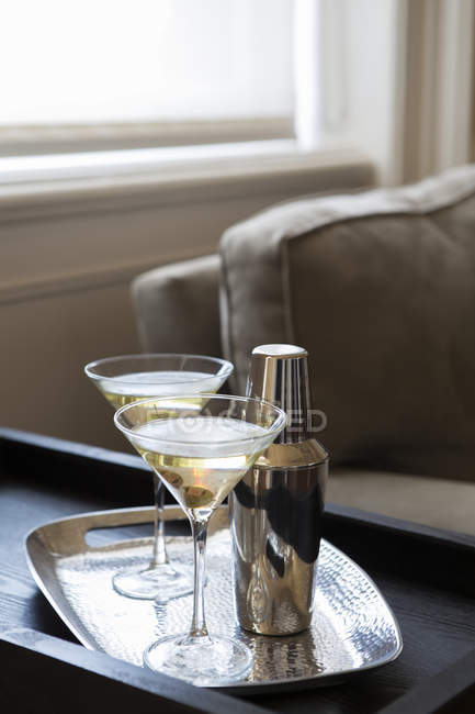Two garnished cocktails in glasses with shaker on tray in modern living room — Stock Photo