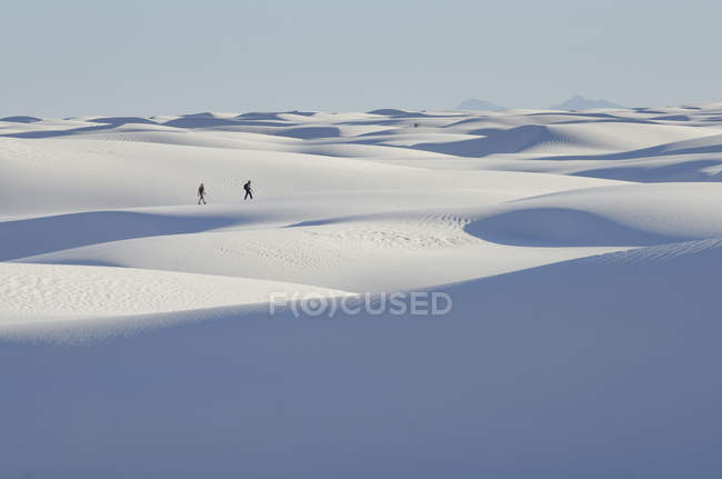 Entfernte Menschen zu Fuß auf schneebedeckter Landschaft, weißem Sand Nationaldenkmal, New Mexico, USA — Stockfoto