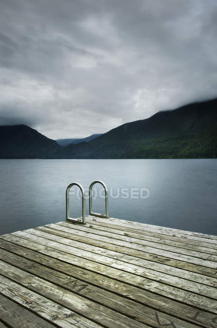 Scala sul molo di legno vicino al lago ancora remoto — Foto stock