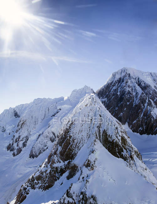 Tapas de montaña cubiertas de nieve bajo luz solar brillante - foto de stock